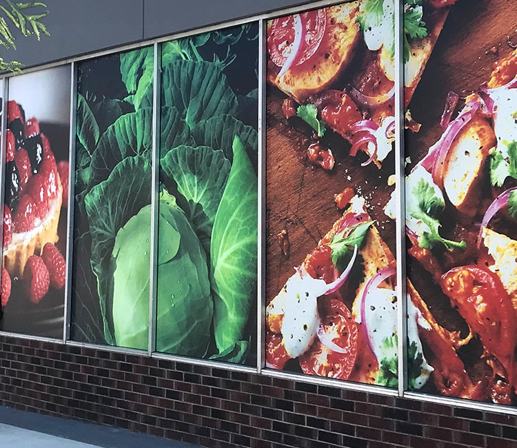 A vibrant display featuring fresh produce, including cabbage, tomatoes, and a dessert with berries, enhancing a storefront's appeal.